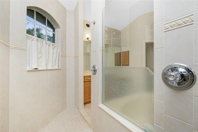 bathroom featuring a tile shower, vanity, and tile walls