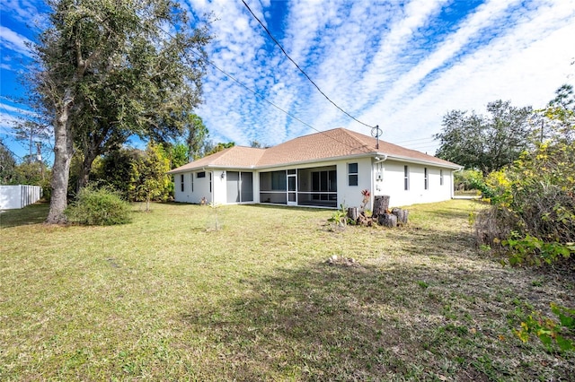 rear view of house featuring a yard and a sunroom