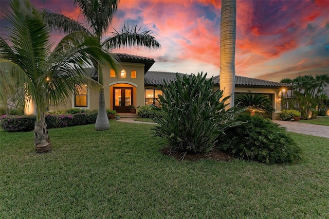 mediterranean / spanish home with a lawn, french doors, and a garage