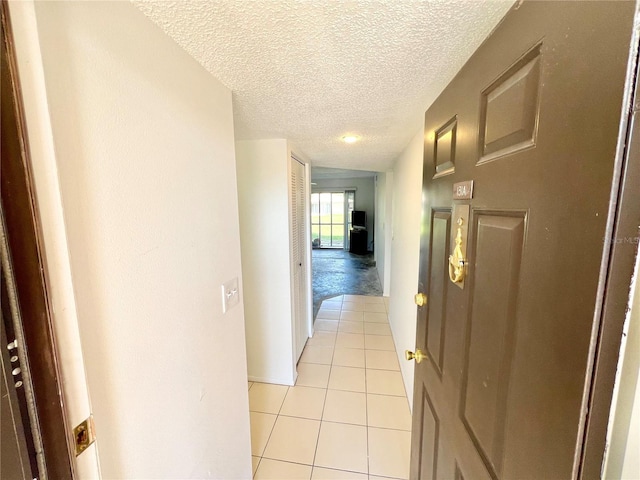 hallway with light tile patterned flooring and a textured ceiling