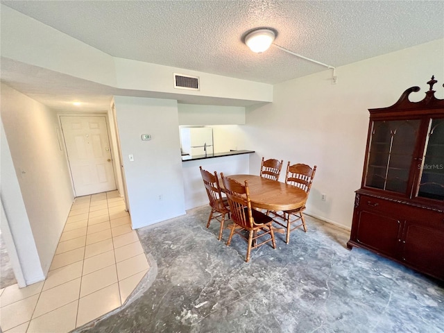 dining area featuring a textured ceiling and light tile patterned floors