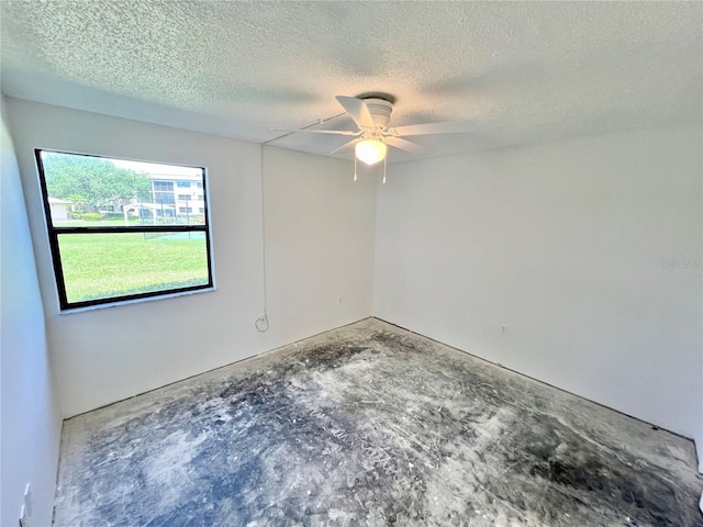 spare room featuring a textured ceiling, concrete flooring, and ceiling fan