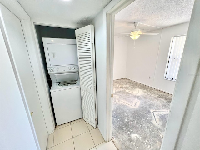 laundry area with stacked washer and dryer, a textured ceiling, ceiling fan, and light tile patterned floors