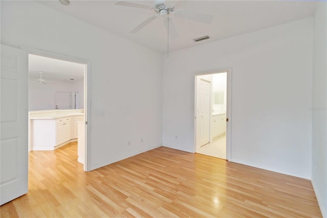 empty room with ceiling fan and light hardwood / wood-style flooring