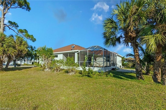 back of property featuring glass enclosure and a yard