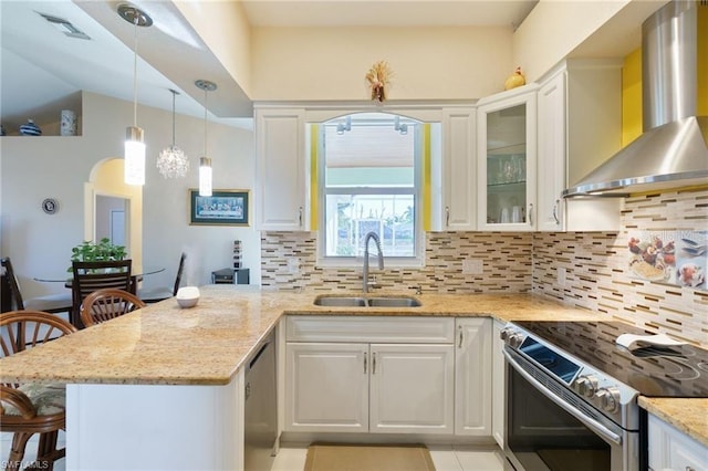 kitchen featuring appliances with stainless steel finishes, white cabinets, a kitchen bar, and wall chimney exhaust hood