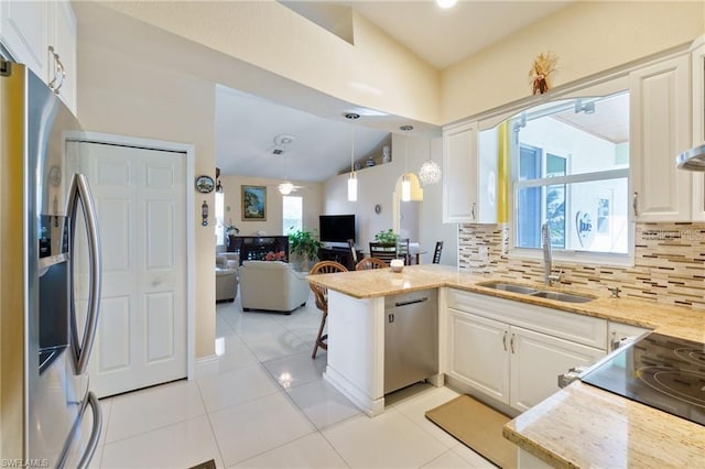 kitchen with stainless steel appliances, sink, white cabinets, vaulted ceiling, and kitchen peninsula