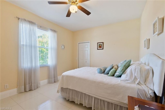 tiled bedroom with ceiling fan and a closet