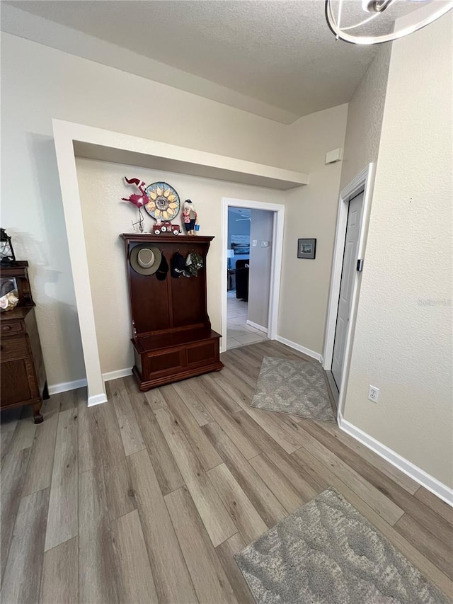 corridor with a textured ceiling and light wood-type flooring