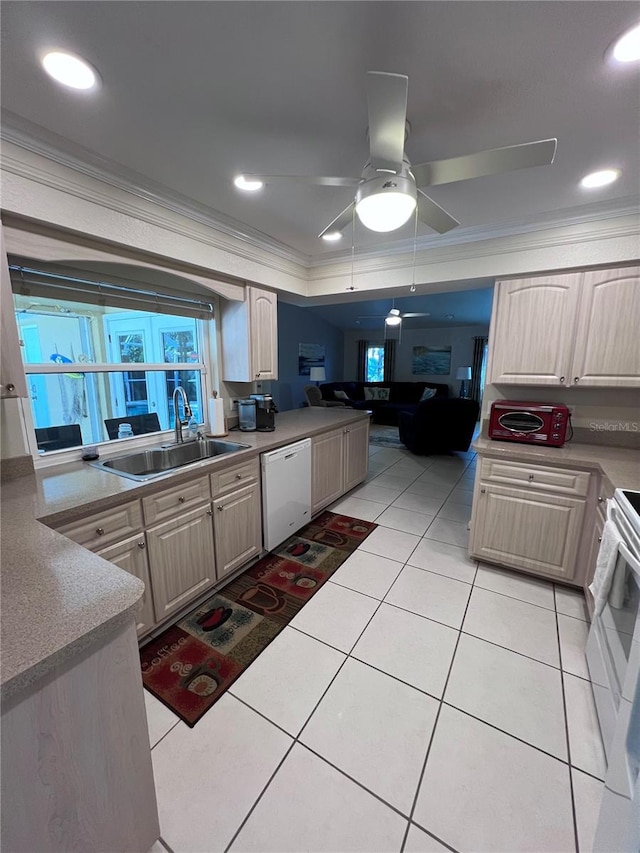 kitchen with sink, light tile patterned floors, a raised ceiling, crown molding, and white appliances