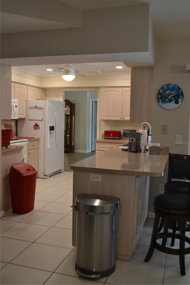 kitchen with a kitchen breakfast bar, light tile patterned floors, ceiling fan, kitchen peninsula, and white appliances