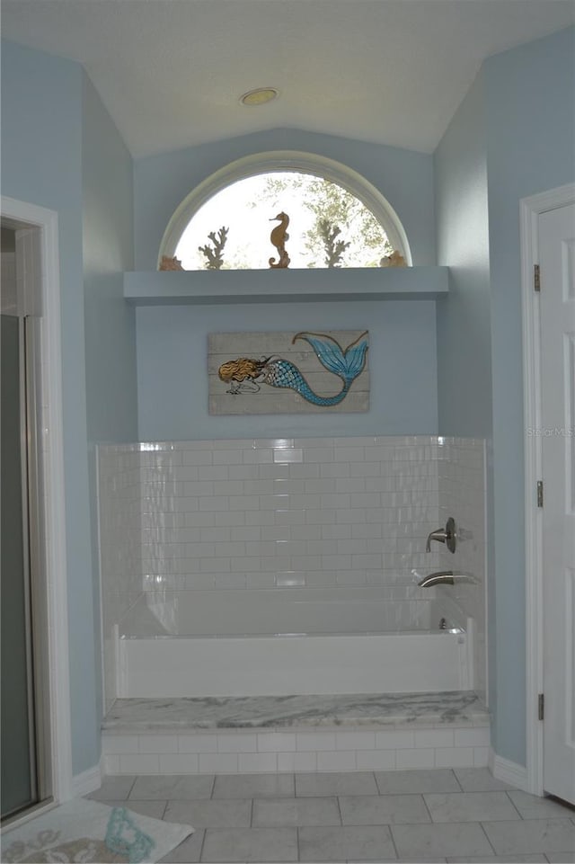 bathroom with a relaxing tiled tub and tile patterned flooring