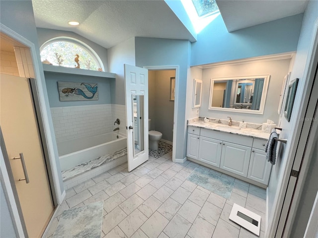 bathroom with toilet, a textured ceiling, vanity, a tub, and vaulted ceiling with skylight