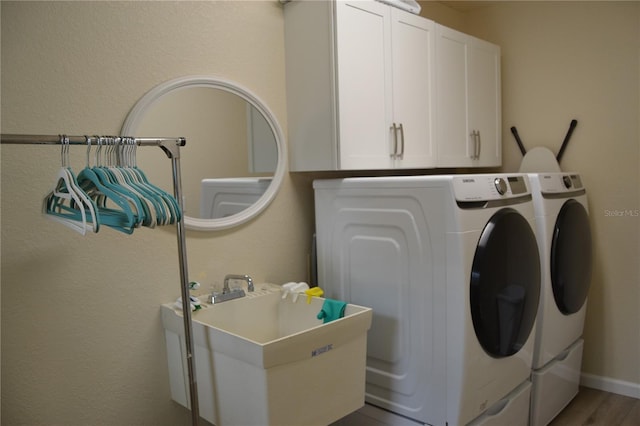 clothes washing area featuring cabinets, wood-type flooring, sink, and washer and clothes dryer