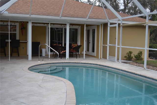 view of pool with french doors, a patio, and glass enclosure