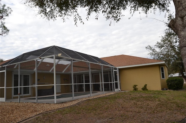 rear view of house featuring a lanai and a lawn