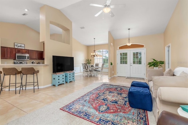 living room featuring vaulted ceiling, light tile patterned flooring, ceiling fan with notable chandelier, and french doors