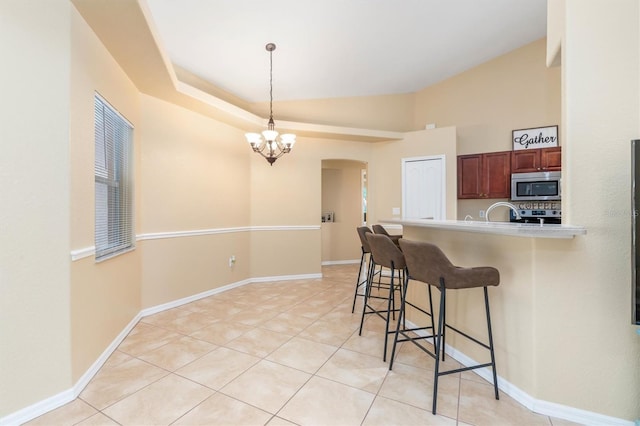 kitchen with decorative light fixtures, stainless steel appliances, an inviting chandelier, a breakfast bar, and light tile patterned floors