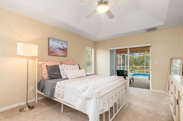 bedroom featuring ceiling fan, access to exterior, light colored carpet, and a raised ceiling