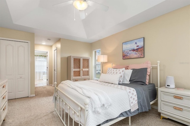 bedroom with ceiling fan, light colored carpet, multiple windows, and a raised ceiling