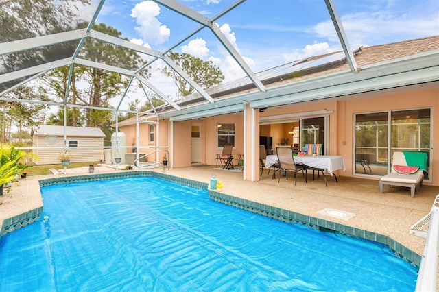 view of pool featuring a storage shed, a patio area, and glass enclosure