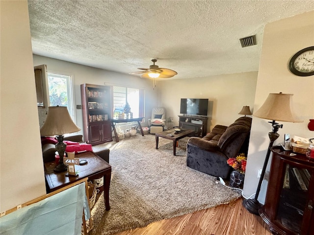 living room featuring a textured ceiling, hardwood / wood-style floors, and ceiling fan