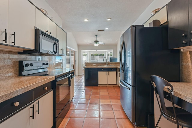 kitchen featuring backsplash, a textured ceiling, vaulted ceiling, white cabinets, and black appliances