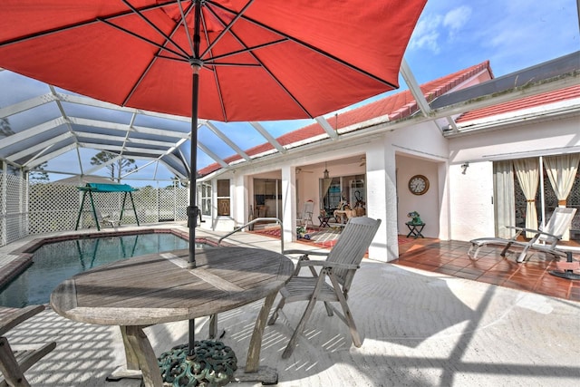 exterior space featuring glass enclosure, ceiling fan, and a patio