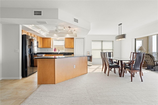 kitchen featuring black fridge, decorative light fixtures, a raised ceiling, ornamental molding, and sink