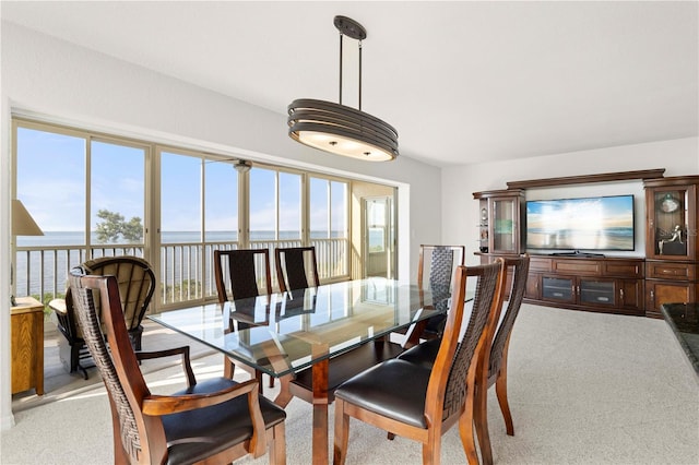 dining area with light colored carpet and a water view