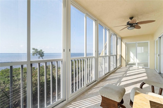 sunroom / solarium with ceiling fan and a water view