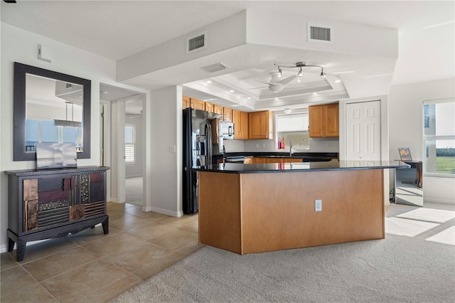 kitchen featuring a center island, light tile patterned floors, a tray ceiling, sink, and black fridge with ice dispenser