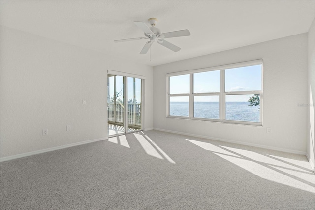 carpeted empty room featuring ceiling fan and a water view