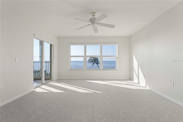 spare room with ceiling fan, a water view, plenty of natural light, and carpet flooring