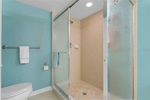 bathroom featuring toilet, a shower with door, and tile patterned floors