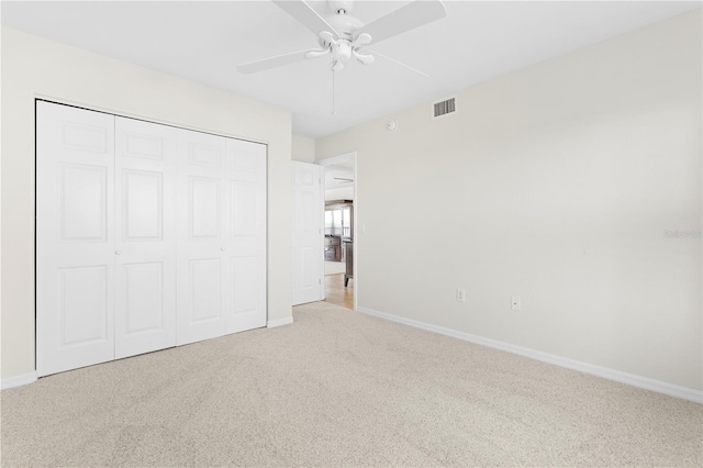 unfurnished bedroom featuring light carpet, a closet, and ceiling fan