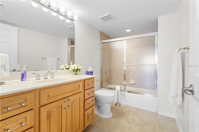 full bathroom with toilet, tile patterned floors, vanity, shower / bath combination with glass door, and a textured ceiling