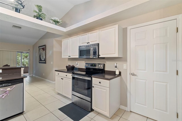 kitchen with white cabinets, stainless steel appliances, vaulted ceiling, and light tile patterned floors