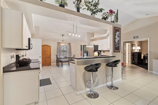 kitchen featuring appliances with stainless steel finishes, a breakfast bar, pendant lighting, white cabinets, and light tile patterned flooring