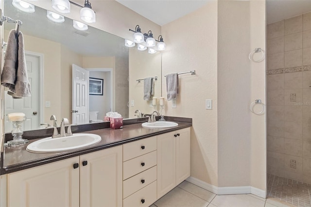 bathroom with tile patterned flooring, tiled shower, and vanity