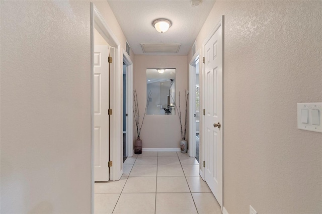 hallway with a textured ceiling and light tile patterned floors