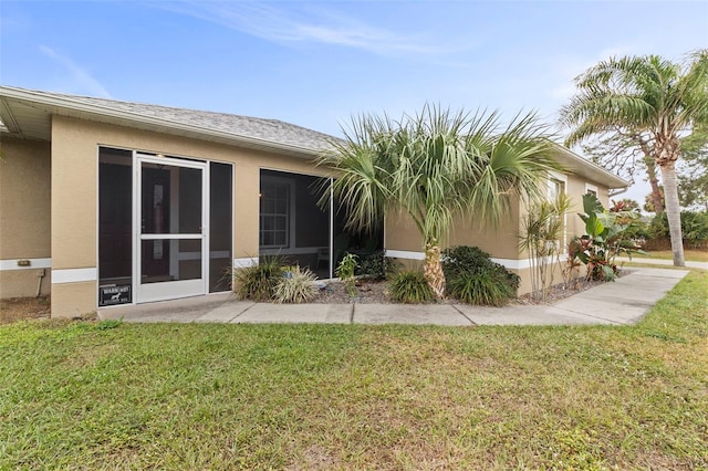 back of property with a yard and a sunroom