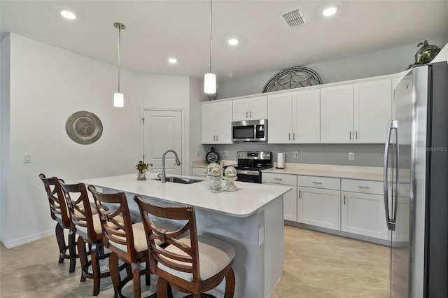 kitchen featuring decorative light fixtures, a center island with sink, sink, stainless steel appliances, and white cabinets