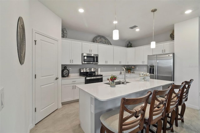 kitchen with decorative light fixtures, a center island with sink, sink, white cabinetry, and stainless steel appliances