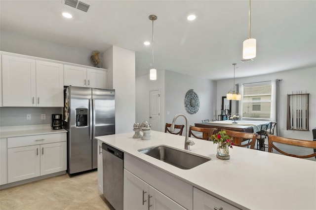 kitchen featuring decorative light fixtures, white cabinets, sink, and stainless steel appliances