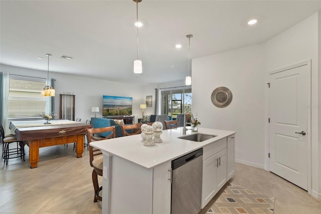 kitchen with pendant lighting, white cabinetry, sink, stainless steel dishwasher, and a center island with sink