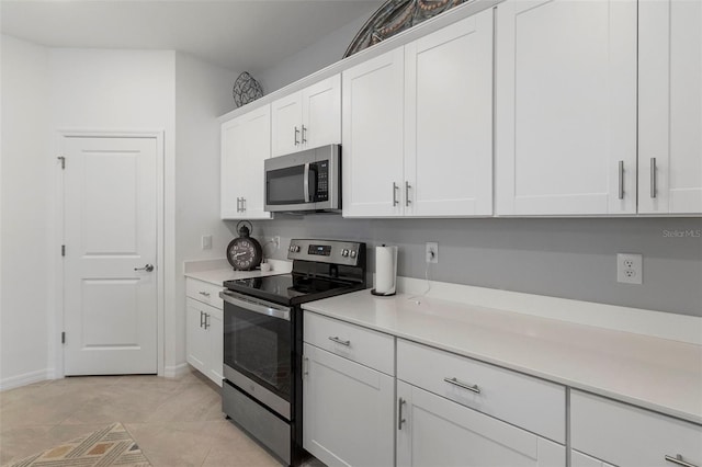 kitchen featuring appliances with stainless steel finishes, light tile patterned flooring, and white cabinetry