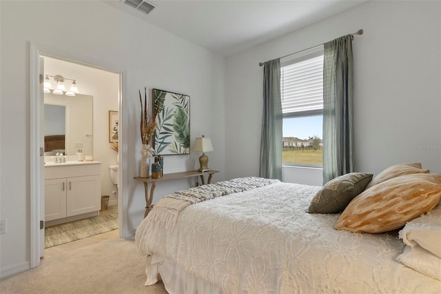 bedroom with light colored carpet, connected bathroom, and sink