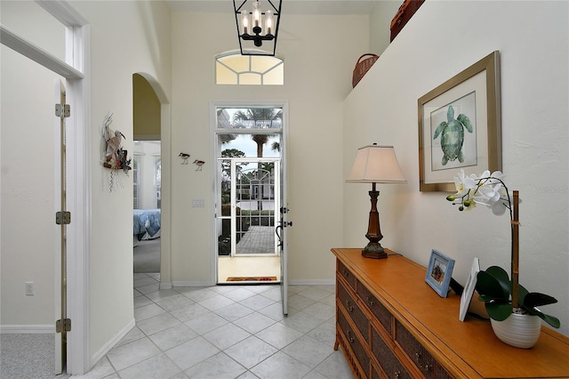 tiled entryway featuring a chandelier and a high ceiling