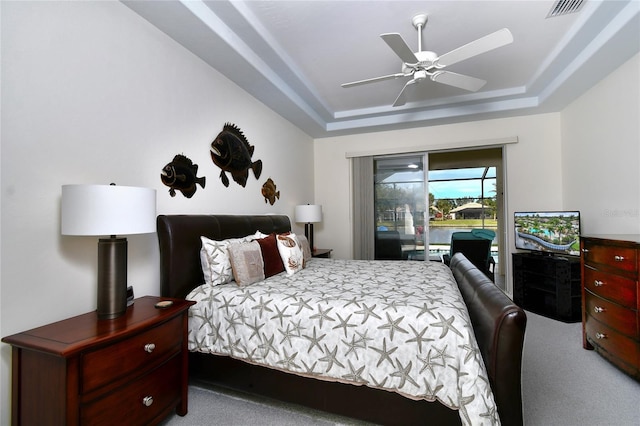 carpeted bedroom with access to outside, ceiling fan, and a raised ceiling